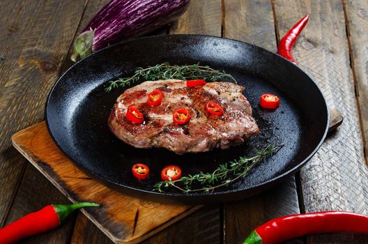 Cooking a steak in a frying pan with thyme and chilli. Stock image.