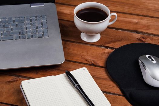 Cup of coffee and laptop on wooden table. Stock image.