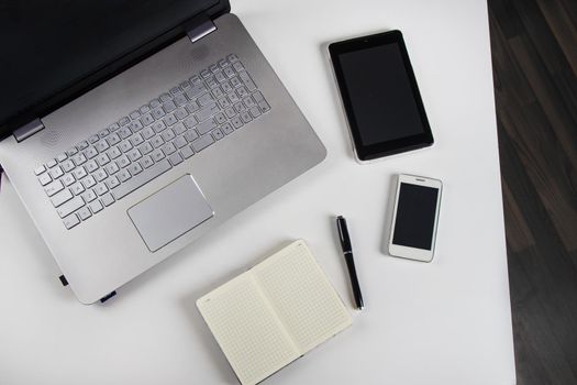 Laptop and notebook on a white table. Stock image.