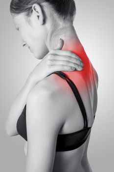 Closeup view of a young woman with shoulder or neck pain on gray background. Black and white photo with red dot