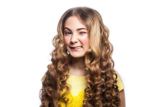 Portrait of winky girl with wavy hairstyle and yellow t shirt. studio shot isolated on white background.