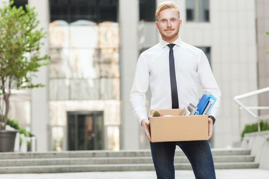 Well dressed young adult businessman, going to new job, smiling and looking at camera. Outdoor