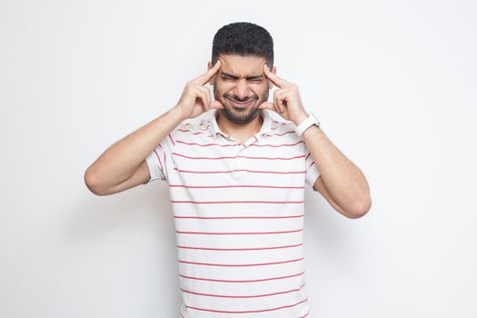 headache or confution. Portrait of confused handsome bearded young man in striped t-shirt standing, holding his painful head or thinking. indoor studio shot, isolated on white background.