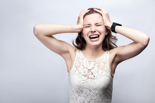 Portrait of beautiful woman with freckles and white dress and smart watch with headache pain on silver gray background. healthcare and medicine concept.