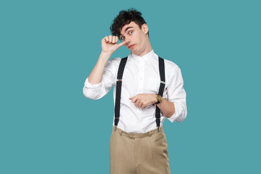 Funny crazy man with looking at camera. Portrait of handsome hipster curly young businessman in classic casual white shirt and suspender standing. indoor studio shot isolated on blue background.