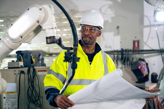 African American factory worker working with adept robotic arm in a workshop . Industry robot programming software for automated manufacturing technology .
