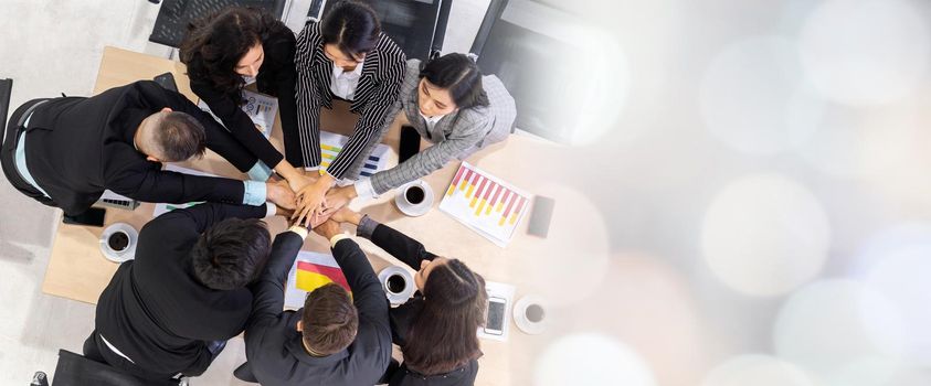 Happy business people celebrate teamwork success together with joy at office table shot from top view . Young businessman and businesswoman workers express cheerful victory in broaden view .