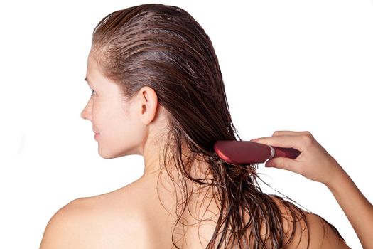 Young beautiful woman with white towel and freckles combing her brown wet hair after showering. studio shot. isolated on white background.