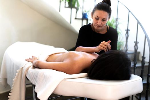 Latina female massage therapist using arm to give back massage to caucasian woman. Copy space. Wellness and bodycare concept.