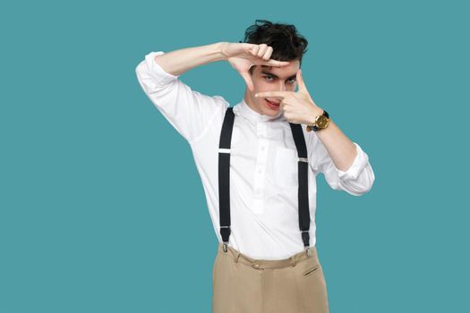 Focus crop composition gesture man looking at camera. Portrait of handsome hipster curly young businessman in classic casual white shirt and suspender standing. studio shot isolated on blue background