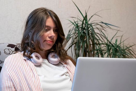 caucasian happy cute girl with headphones is using a laptop. Watch movies online. Distance education. Video call. Video chat with your family