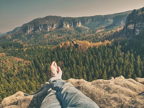 Naked male crossed legs take a rest on peak of rock. Outdoor activities.  