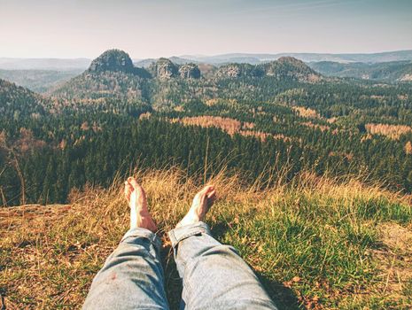 Tired hikers legs without shoes. Traveler relaxing with mountains view on background