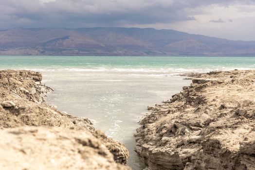 Sinkhole filled with turquoise water, near Dead Sea coastline. Hole formed when underground salt is dissolved by freshwater intrusion, due to continuing sea-level drop. . High quality photo