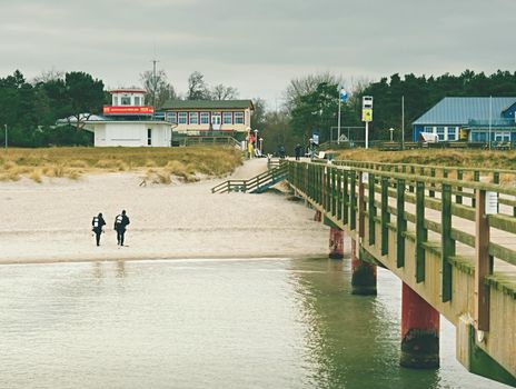 Prerow Germany - January 25 2018: Couple of sea divers walk from sea to beach. End of diving lesson.