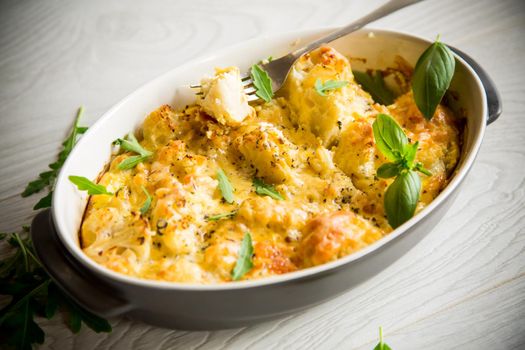 baked cauliflower with vegetables and cheese and scrambled eggs in a ceramic dish