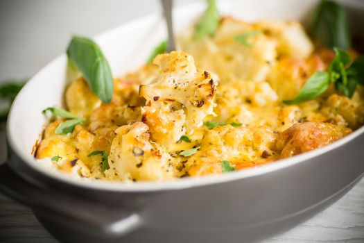 baked cauliflower with vegetables and cheese and scrambled eggs in a ceramic dish