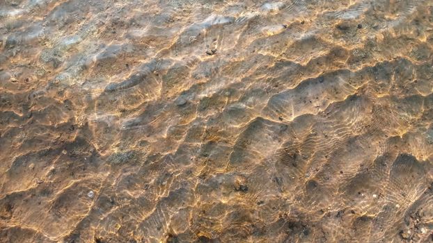 Top view on colorful pebbles covered by water. Close up view of smooth round pebble stones on the beach.