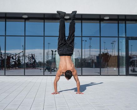 A man doing a handstand outdoors against of panoramic windows