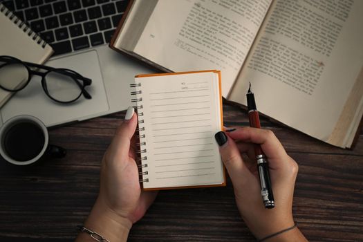 Close up view woman holding empty notepad and pen.