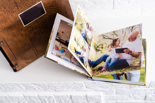 Luxury wooden photo book, wooden box with summer photos printed and flash card on linen natural background. Family memories photobook. Save your summer vacation memories. Photo album with wooden cover.