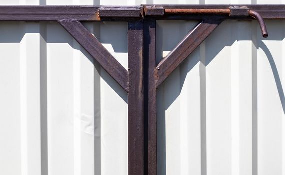 Latch on the gate. Design for locking the gate from the inside. Old rusty padlock on a metal fence. Locking latch on the gate