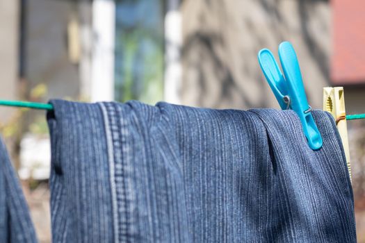 Jeans hang on a clothesline on a sunny summer day. View of freshly washed jeans