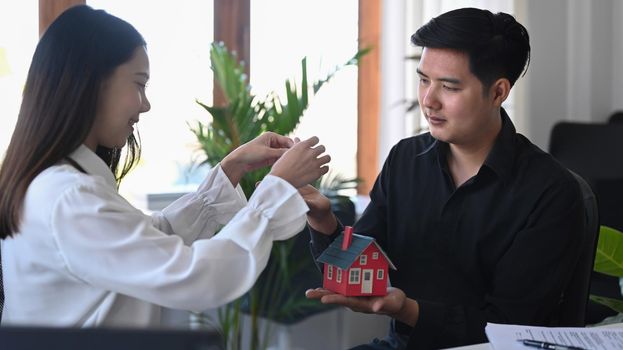 Happy young asian man receiving keys from real estate agent.