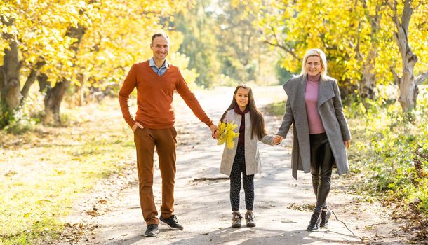 Family playing in autumn park having fun.