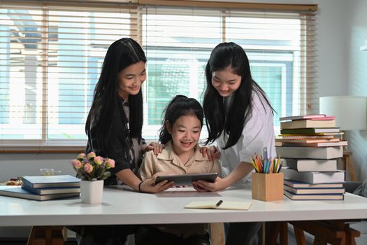 Three asian children doing their homework with digital tablet together.