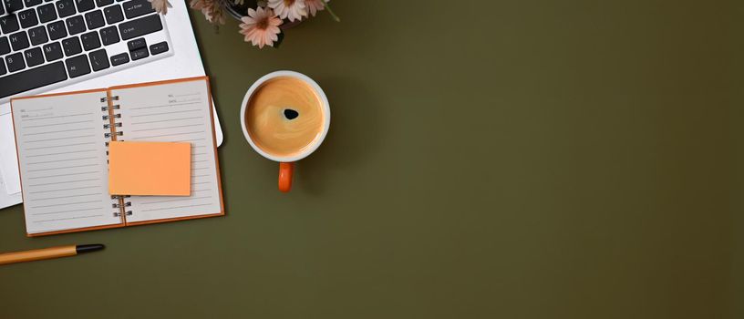 Notebook, sticky note, laptop computer and coffee cup on green background with copy space.