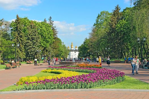 people have a rest in city park with beds of tulips in spring. Chernihiv town with blossoming tulips in spring. Beautiful Ukrainian town. Colors of spring. City decorations. People going in city park