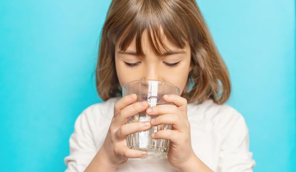 Child girl drinks water from a glass. Selective focus.