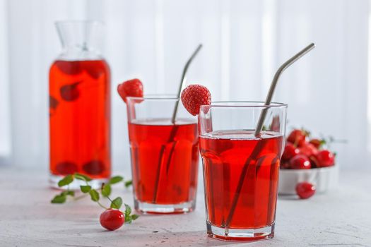 Red refreshing drink with mint on a gray background. A colorful summer non - alcoholic refreshing drink made from berries .