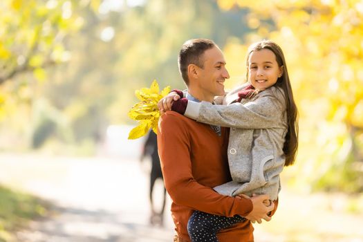 Happy joyful young father with his little daughter. Father and little kid having fun outdoors, playing together in autumn park. Dad with his child laughing and enjoying nature.