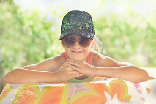Girl in a cap and glasses on an inflatable circle