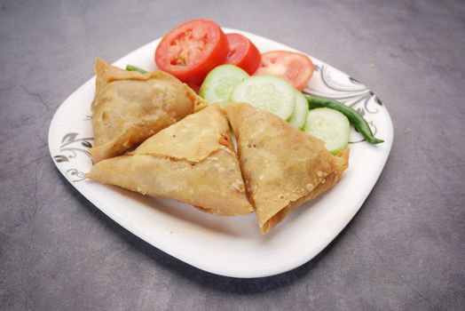 top view of Indian samosa and tomato on a plate .