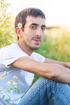 man with flowers in a camomile field. Selective focus.