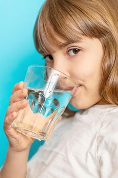 Child girl drinks water from a glass. Selective focus.