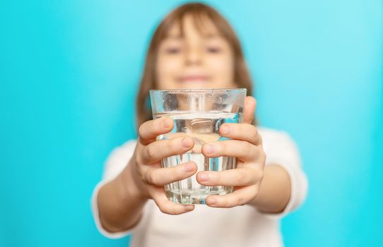 Child girl drinks water from a glass. Selective focus.