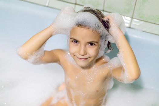 The child bathes in a bathtub soapy water. Selective focus.