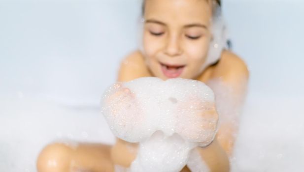 The child bathes in a bathtub soapy water. Selective focus.