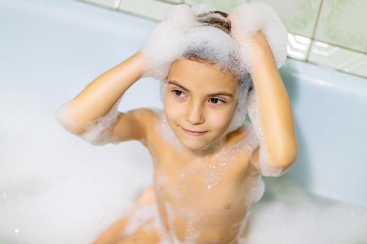 The child bathes in a bathtub soapy water. Selective focus.