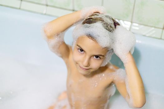 The child bathes in a bathtub soapy water. Selective focus.
