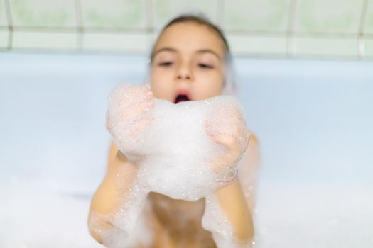The child bathes in a bathtub soapy water. Selective focus.