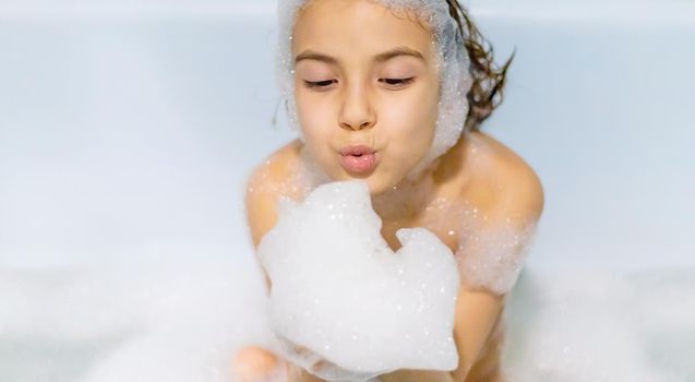 The child bathes in a bathtub soapy water. Selective focus.