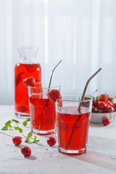 Red refreshing drink with mint on a gray background. A colorful summer non - alcoholic refreshing drink made from berries . Vertical photo