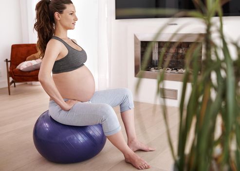 Shot of a young pregnant woman exercising at home.