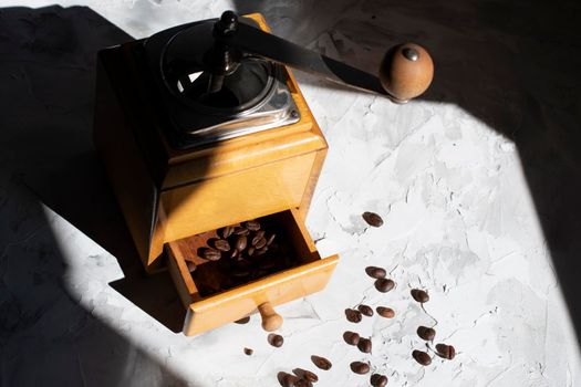 whole roasted coffee beans in the drawer of a vintage wooden coffee grinder in the sun, close up. High quality photo