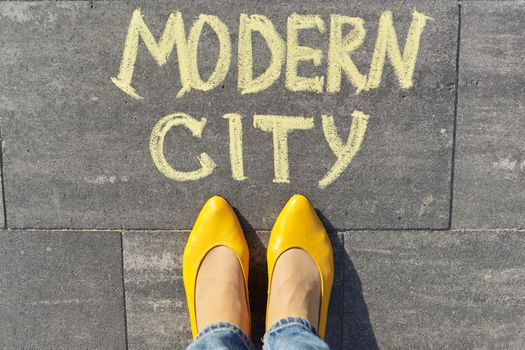 Modern city concept, top view on woman legs and text written in chalk on gray sidewalk.